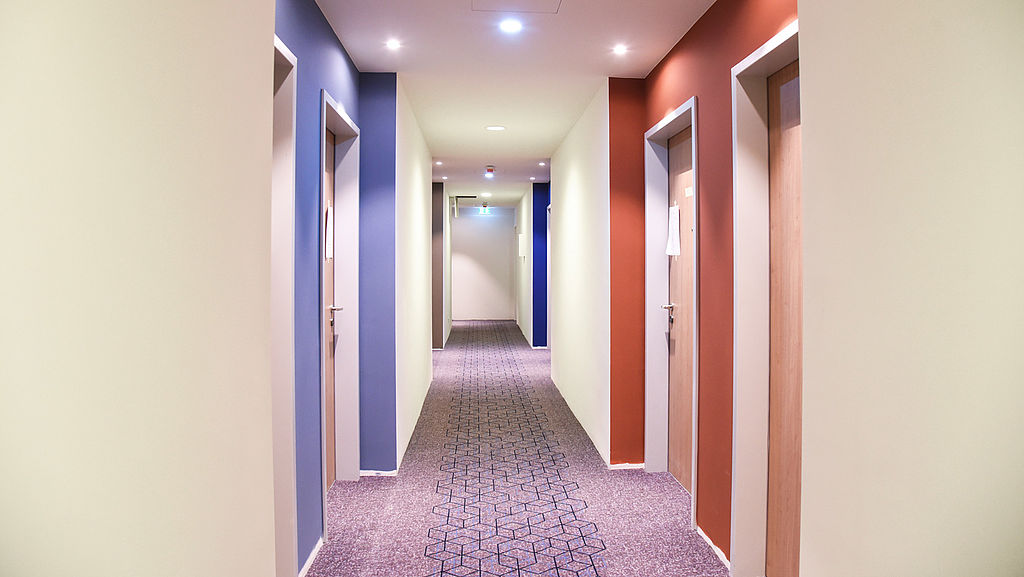 Hotelflur mit bunt umrahmten Zimmereingängen