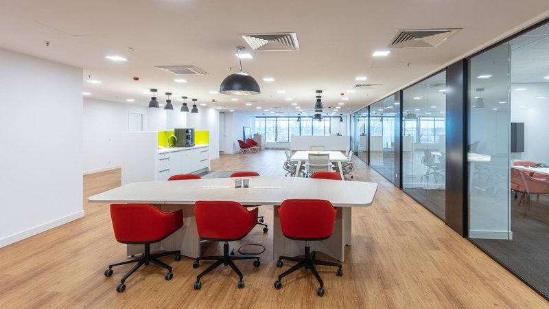 Großraumbüro mit Konferenztisch und roten Bürosesseln